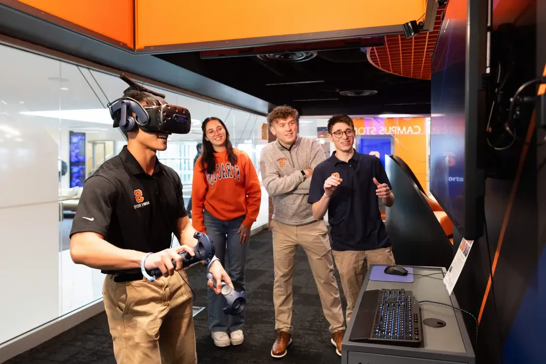 Students watching a student use a VR gaming set in the Esports Center.